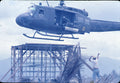 Huey helicopter hovering over a scaffold tower as a crew member signals, Apocalypse Now behind-the-scenes photo