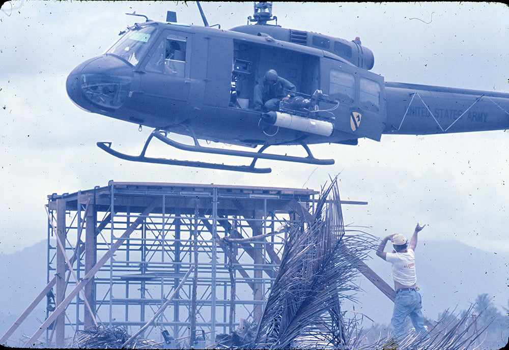Huey helicopter hovering over a scaffold tower as a crew member signals, Apocalypse Now behind-the-scenes photo
